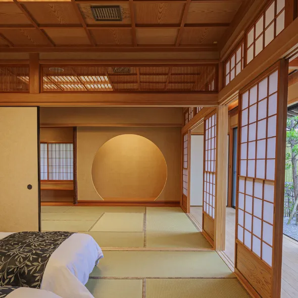 Japanese‑style bedroom with twin beds, tatami flooring, shoji doors, and a garden view at a luxury ryokan on Awaji Island.
