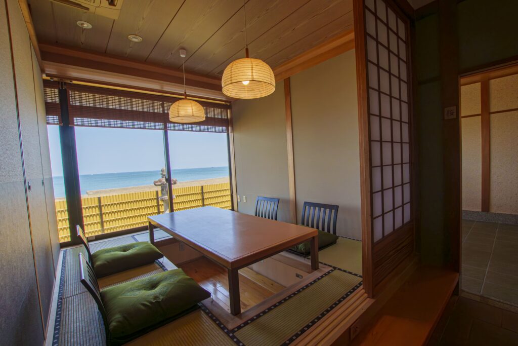 Traditional tatami dining room with low table, shoji doors, and ocean view at a luxury Japanese ryokan with private onsen on Awaji Island.