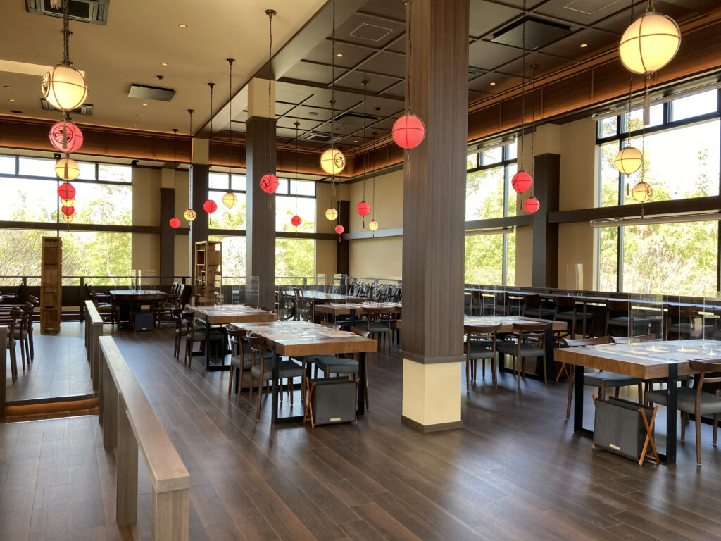 The spacious dining area of Aman no Shokutaku Sajiki, featuring rich wood decor and hanging lantern lighting.