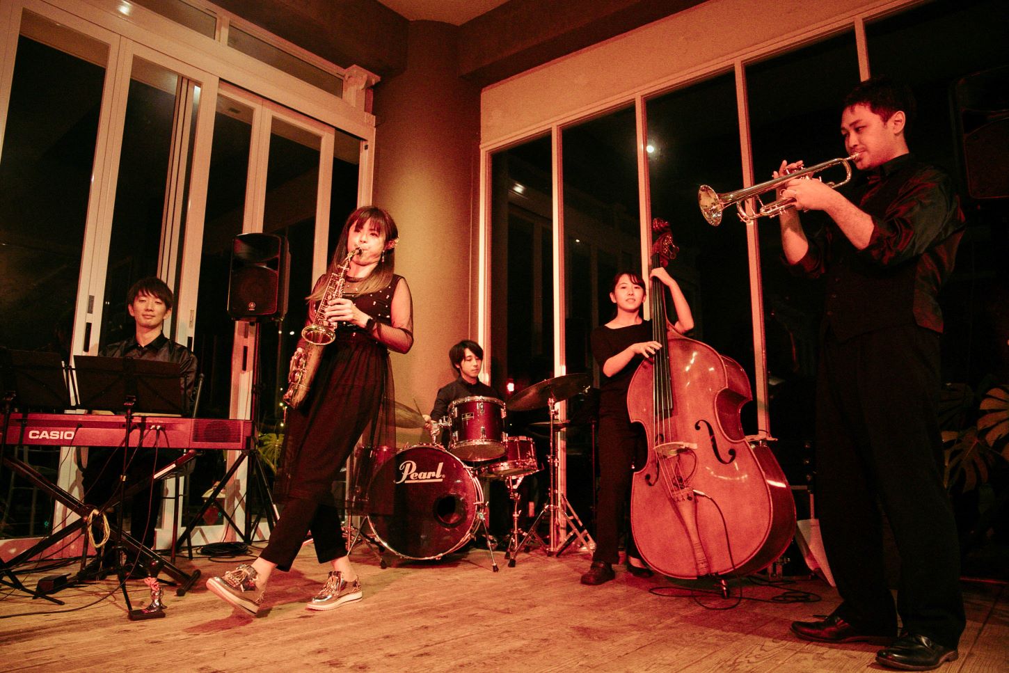 A live jazz band performing on stage at Ocean Terace, featuring a saxophonist, trumpet player, bassist, drummer, and keyboardist.