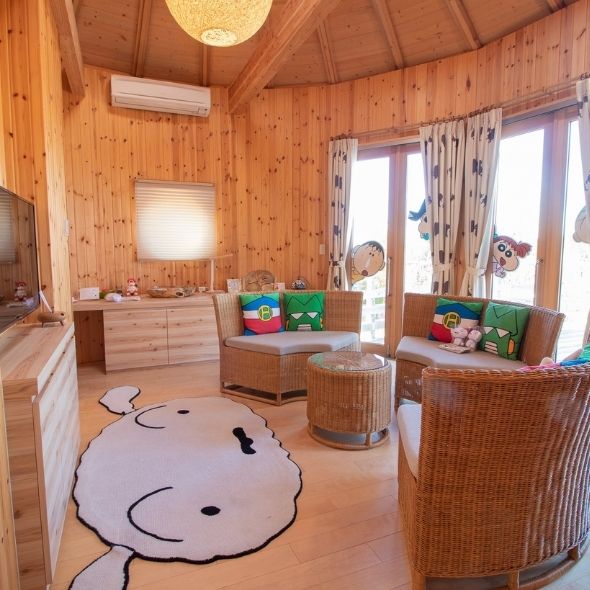 Crayon Shin-chan themed lounge with sofa, character pillows, round coffee table and terrace view at Grand Chariot Awaji Island cocoon villa