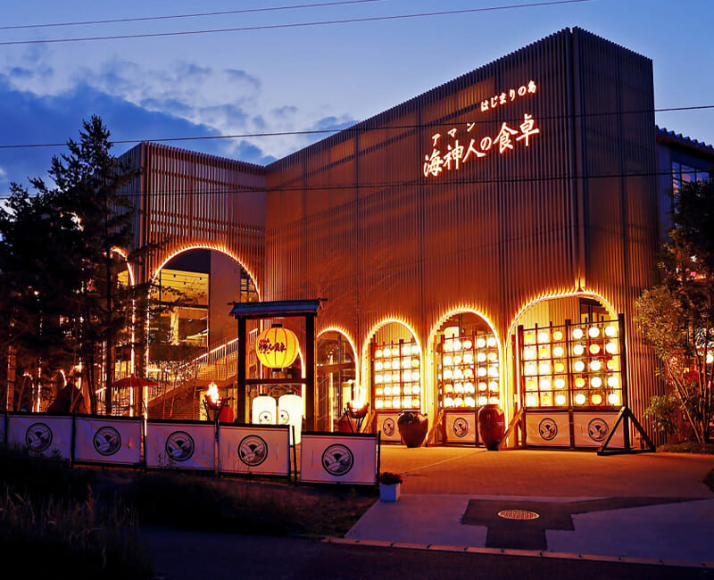 The beautifully illuminated exterior of Aman no Shokutaku restaurant on Awaji Island, glowing at night.