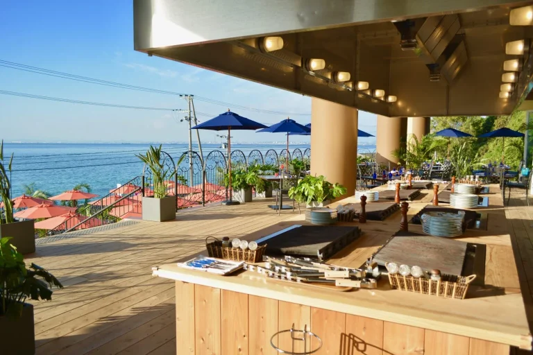 A beautiful sunny outdoor terrace at Ocean Terace, featuring BBQ grill stations and a scenic view of the Seta Inland Sea