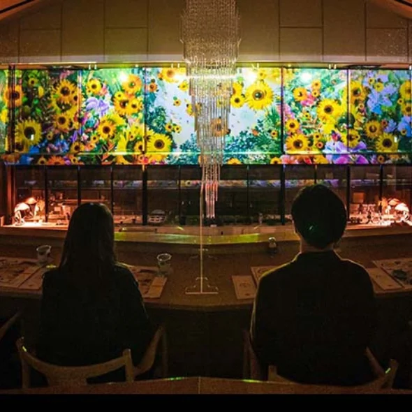 Guests enjoying an immersive dining experience at Aonoya on Awaji Island with digital art and sunset-inspired lighting.