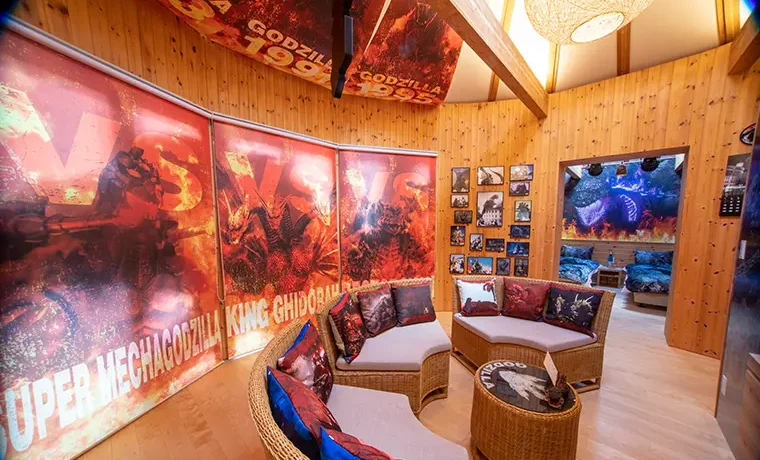 Godzilla Kaiju Land lounge with sofa, monster-themed pillows, large windows with Godzilla visuals and terrace at Grand Chariot Awaji Island