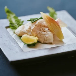 Elegant plate of grilled white fish with lime and myoga garnish served at a luxury Japanese ryokan with private onsen on Awaji Island.