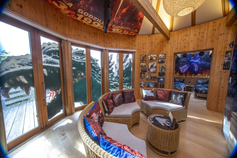 Godzilla themed room at Grand Chariot Awaji Island with large windows, themed décor, sofas with Godzilla pillows, and bedroom with Godzilla artwork