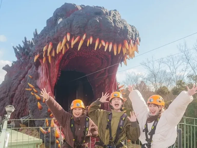Excited visitors in zipline gear prepear to fly toward life size Godzilla at Nijigen no Mori Awaji Island