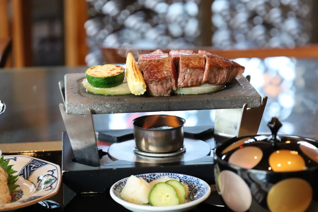 A hot stone grill featuring premium wagyu steak and fresh grilled vegetables at Aman no Shokutaku Sajiki.