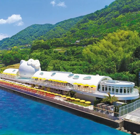 An exterior view of the Hello Kitty Smile facility with a giant white Hello Kitty head structure along the coast of Awaji Island.